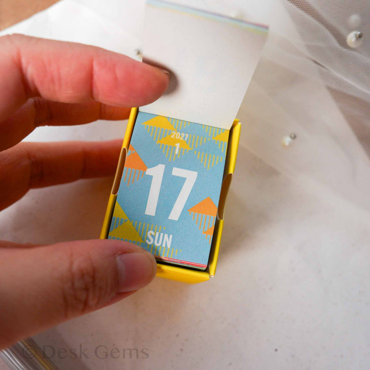 Shinnippon Mini Mini Daily Calendar 2027 Dates open showing January 17 page with blue and yellow triangle pattern
