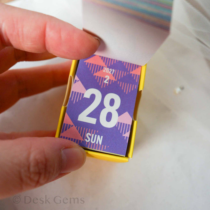 Shinnippon Mini Mini Daily Calendar 2027 Dates open showing February 28 page with purple geometric pattern
