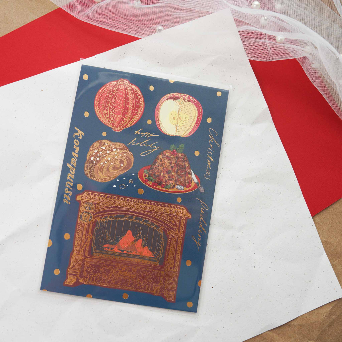 Aya Inoue Christmas postcard with fireplace, Christmas pudding, and holiday treats on dark blue background