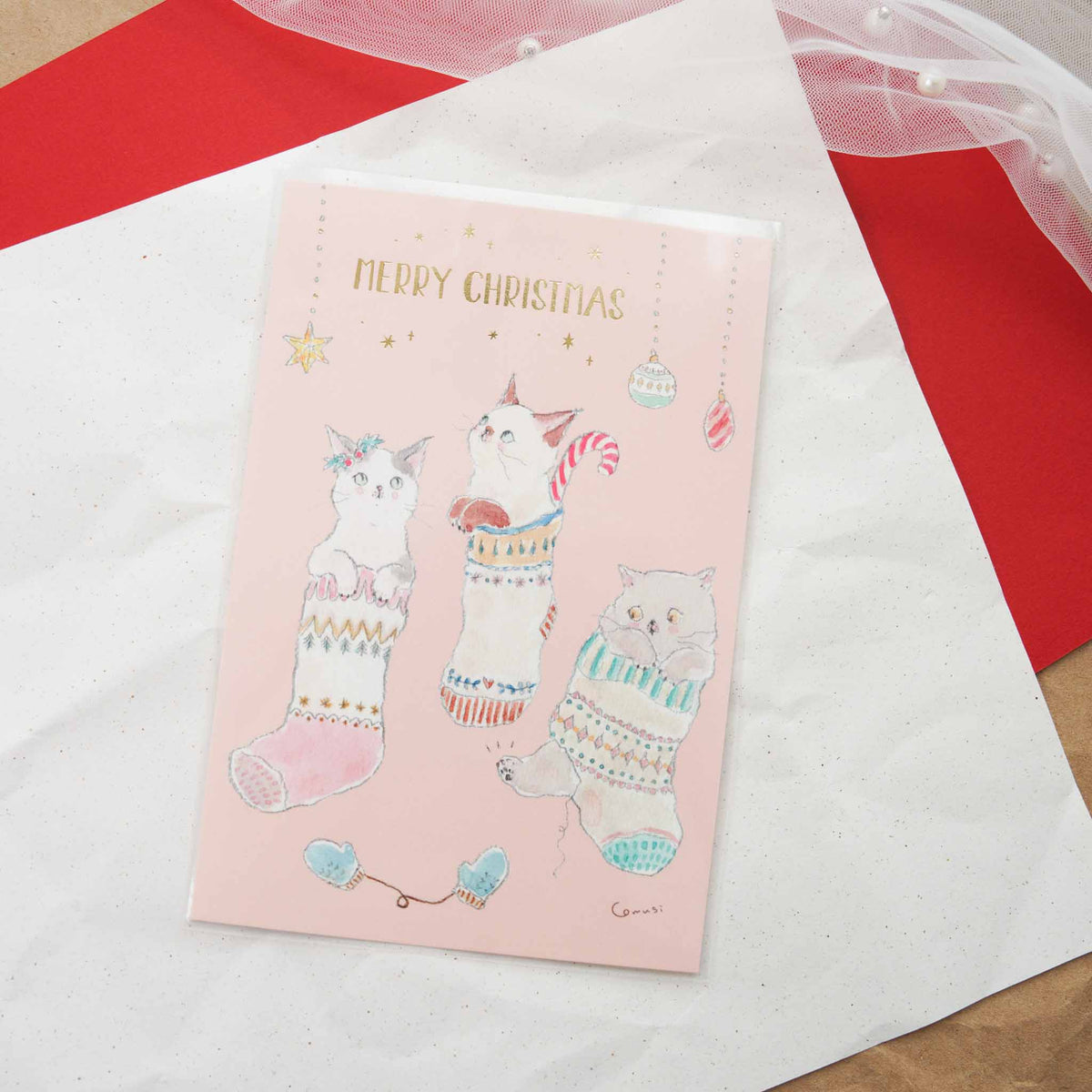 Tocoro Comugi Christmas postcard featuring cats peeking out of cozy knitted stockings